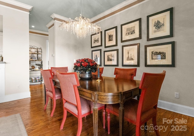 dining space with a notable chandelier, ornamental molding, wood finished floors, recessed lighting, and baseboards