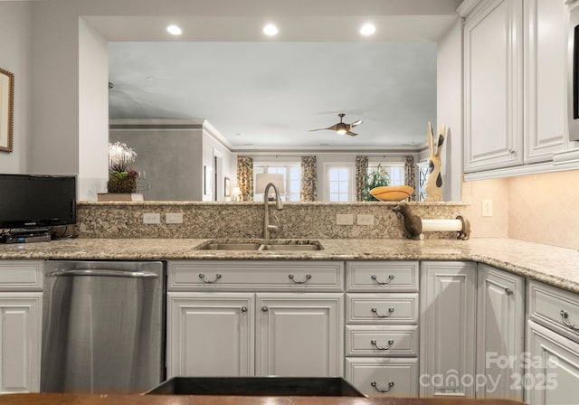 kitchen with a sink, light stone counters, stainless steel dishwasher, and white cabinetry