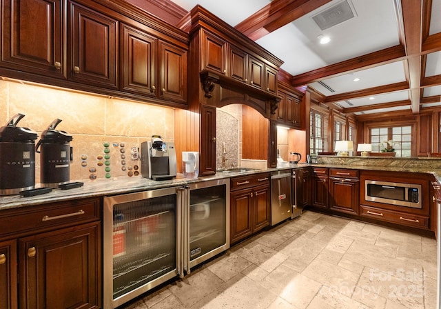 kitchen featuring beverage cooler, stainless steel microwave, visible vents, and a sink