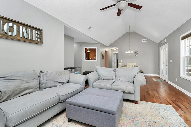 living room with vaulted ceiling, wood finished floors, baseboards, and visible vents