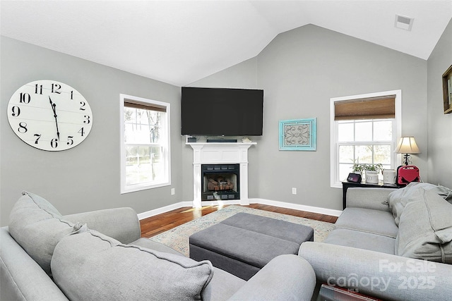 living room featuring visible vents, wood finished floors, a fireplace, and vaulted ceiling