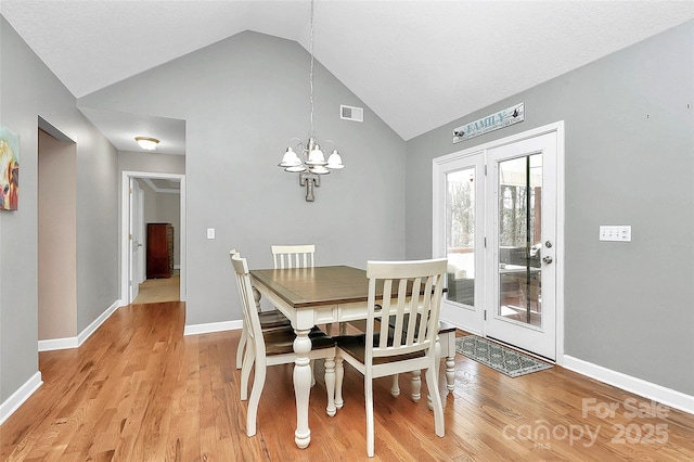 dining area with visible vents, baseboards, light wood-style flooring, and a chandelier