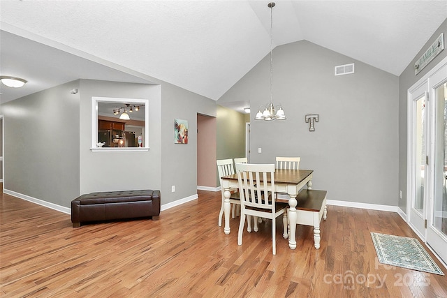 dining area featuring visible vents, baseboards, a chandelier, wood finished floors, and high vaulted ceiling