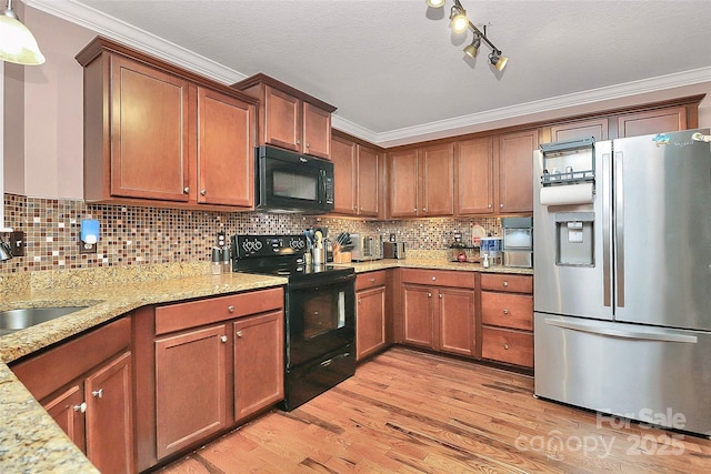 kitchen with light stone counters, a sink, ornamental molding, black appliances, and light wood-type flooring