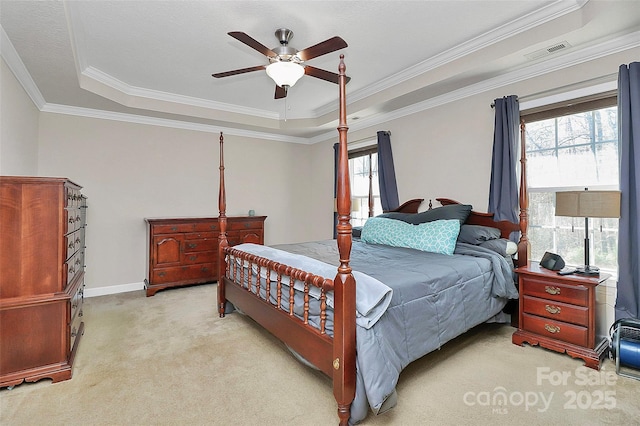 bedroom with visible vents, crown molding, light carpet, a raised ceiling, and a ceiling fan