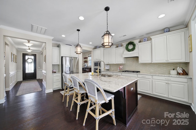 kitchen featuring visible vents, an island with sink, dark wood-type flooring, appliances with stainless steel finishes, and white cabinetry