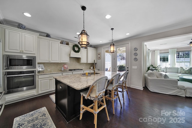 kitchen with appliances with stainless steel finishes, open floor plan, crown molding, and white cabinets