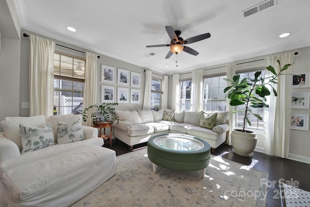 living room with visible vents, plenty of natural light, dark wood-style floors, and crown molding