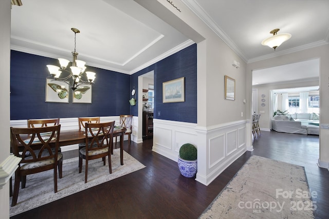 dining space featuring a wainscoted wall, ornamental molding, an inviting chandelier, and wood finished floors