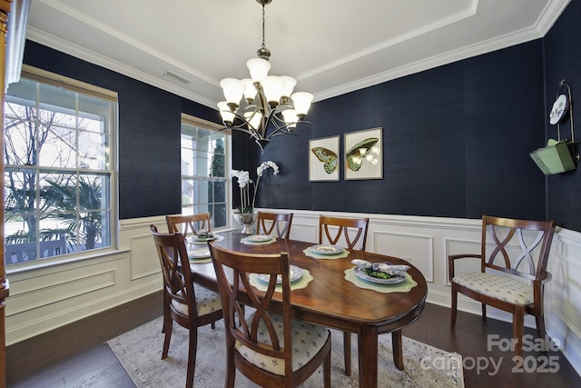 dining room with wood finished floors, a wainscoted wall, visible vents, a decorative wall, and a notable chandelier