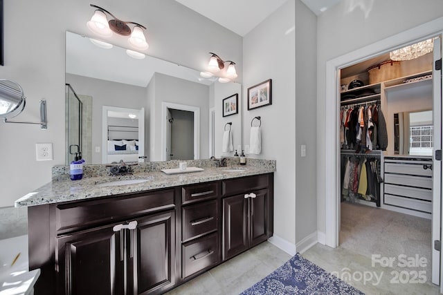 bathroom with double vanity, a walk in closet, and a sink