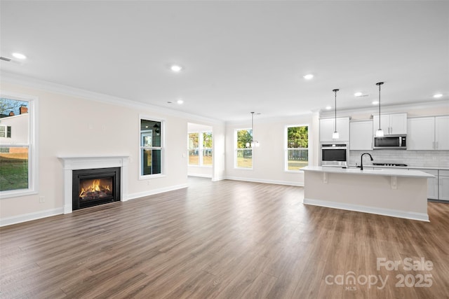 unfurnished living room featuring visible vents, crown molding, a lit fireplace, and wood finished floors