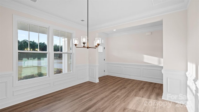 unfurnished room with visible vents, ornamental molding, wainscoting, wood finished floors, and a chandelier