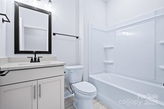 bathroom featuring toilet, shower / tub combination, wood finished floors, and vanity