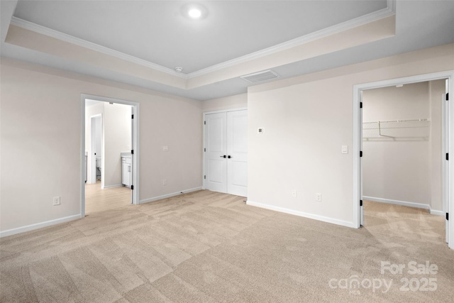 unfurnished bedroom with light carpet, ornamental molding, a raised ceiling, and visible vents