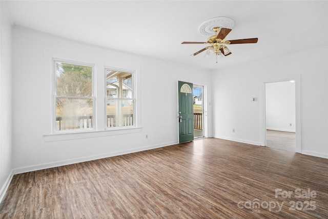 unfurnished room with baseboards, wood finished floors, and a ceiling fan