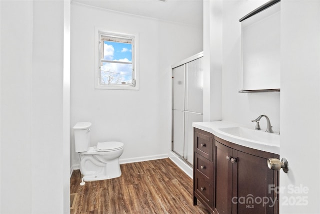 bathroom featuring vanity, toilet, wood finished floors, and a stall shower