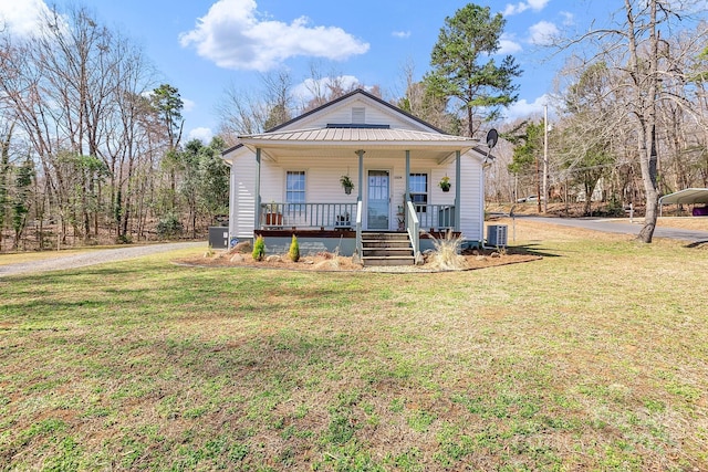 bungalow-style house with a front lawn, a porch, cooling unit, metal roof, and driveway