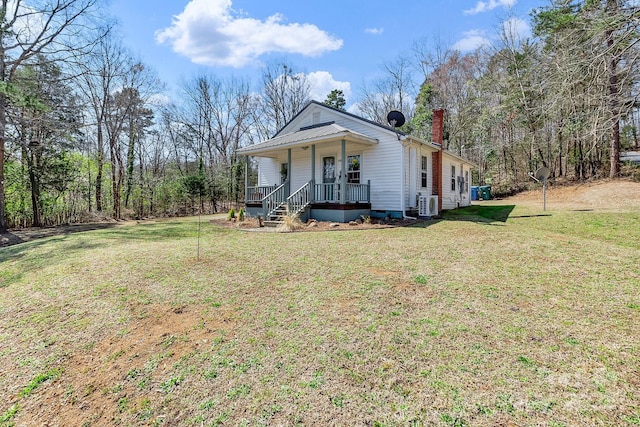 view of front of property with ac unit, a chimney, covered porch, and a front lawn