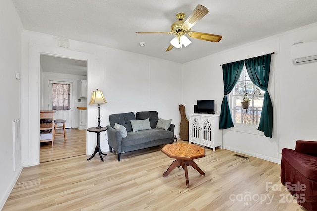 living room with a ceiling fan, a wall unit AC, wood finished floors, and visible vents