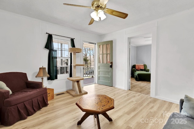 sitting room featuring visible vents, baseboards, ceiling fan, and wood finished floors