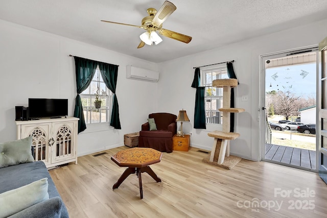 living area featuring a ceiling fan, a wall unit AC, wood finished floors, and visible vents