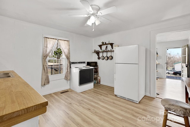 kitchen with visible vents, white appliances, light wood-style floors, and a ceiling fan