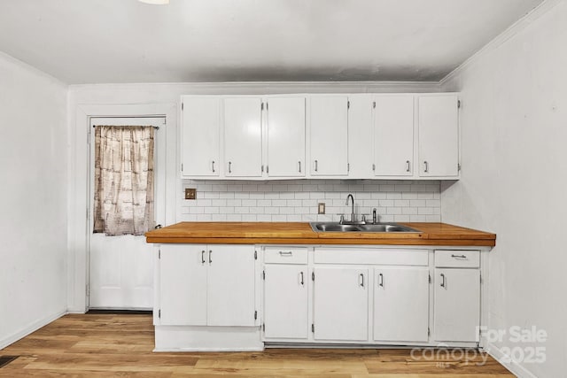 kitchen featuring white cabinets, tasteful backsplash, light wood finished floors, and a sink