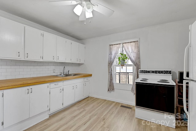 kitchen with light wood finished floors, decorative backsplash, range with electric stovetop, white cabinetry, and a sink