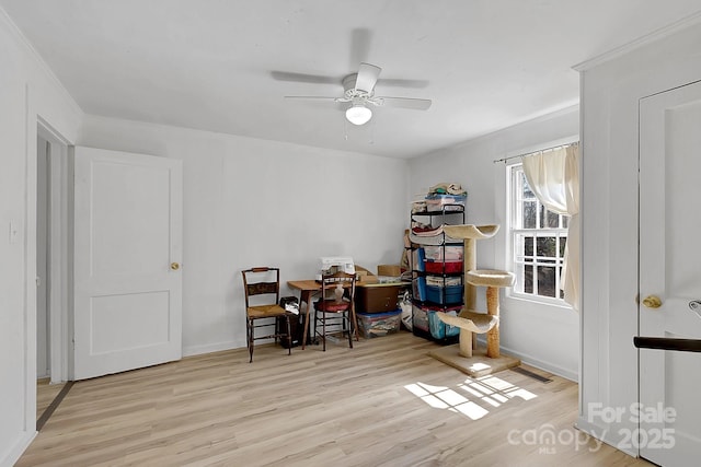 office space with baseboards, crown molding, a ceiling fan, and wood finished floors