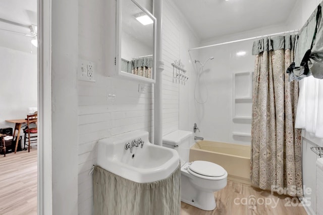 full bath featuring a sink, shower / bathtub combination with curtain, toilet, and wood finished floors