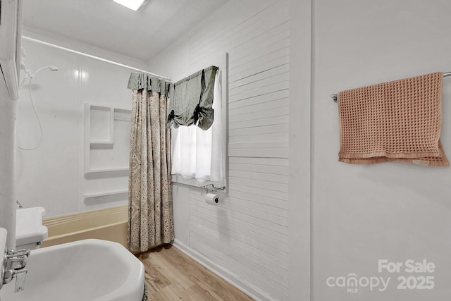 full bath with wood finished floors, shower / bath combo with shower curtain, and a sink