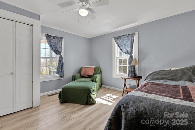 bedroom with crown molding, light wood-style flooring, baseboards, and visible vents