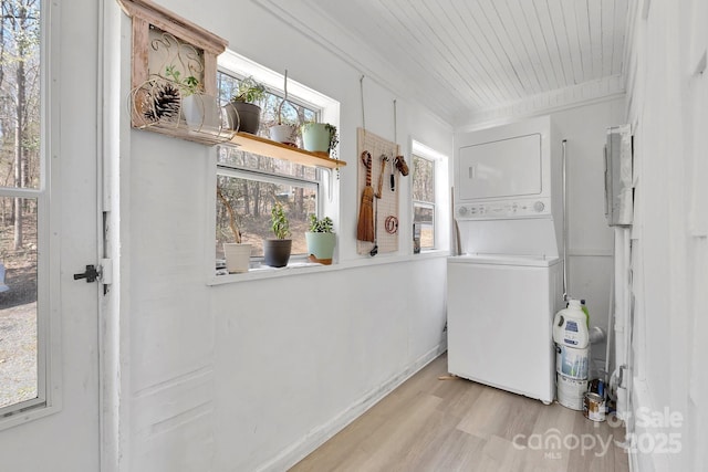 laundry area featuring stacked washer / dryer, baseboards, laundry area, wooden ceiling, and wood finished floors