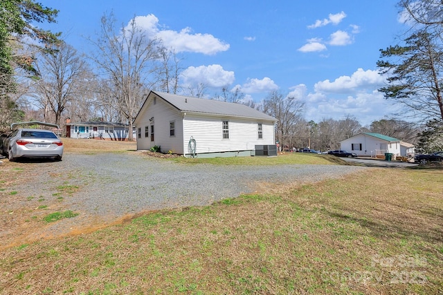 view of property exterior featuring central AC, driveway, metal roof, and a yard