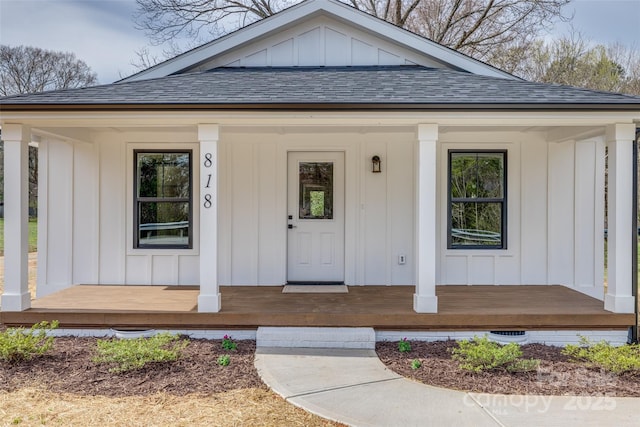 doorway to property with a porch, board and batten siding, and roof with shingles