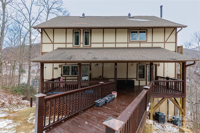 back of property with a deck, central AC unit, roof with shingles, and stucco siding