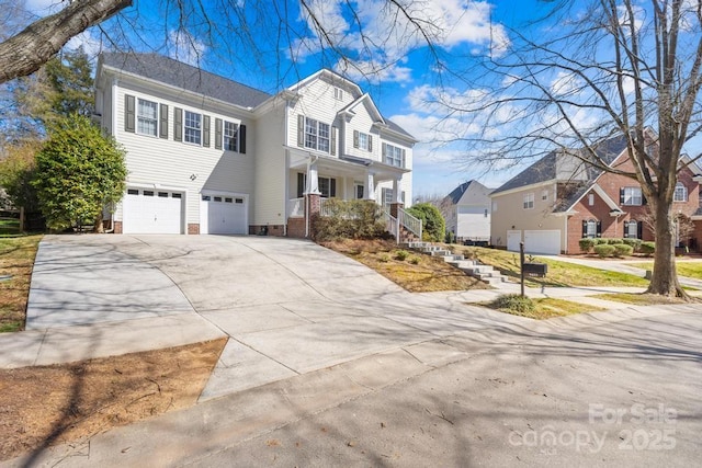 traditional-style home with a garage, a residential view, a porch, and concrete driveway