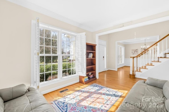 living area featuring visible vents, an inviting chandelier, wood finished floors, and stairs