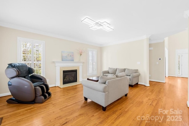 living area featuring light wood finished floors, a fireplace with flush hearth, baseboards, and ornamental molding