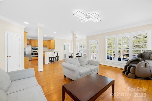 living area featuring baseboards, ornamental molding, recessed lighting, light wood-style floors, and ornate columns