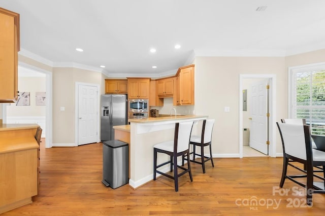 kitchen featuring light wood-type flooring, appliances with stainless steel finishes, a peninsula, and crown molding