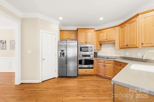 kitchen with ornamental molding, appliances with stainless steel finishes, light wood-style flooring, and a sink