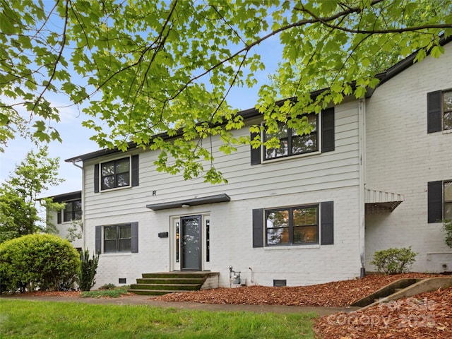 view of front of home with crawl space and brick siding