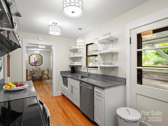 kitchen with open shelves, light wood-style flooring, dark stone counters, a sink, and stainless steel appliances