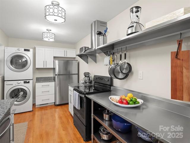 kitchen featuring light wood-type flooring, stacked washer and dryer, stainless steel counters, white cabinetry, and appliances with stainless steel finishes