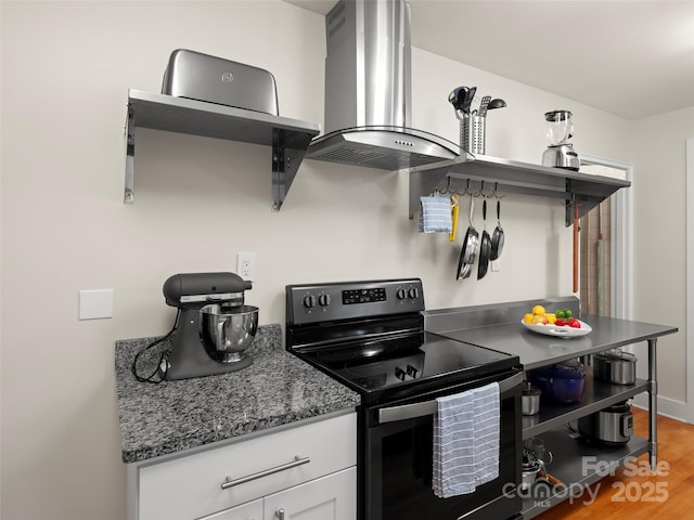 kitchen with stone counters, light wood-style flooring, range with electric stovetop, island range hood, and white cabinets