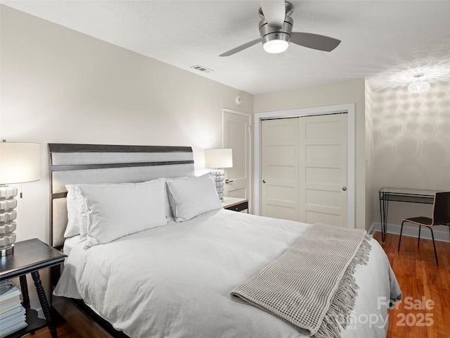 bedroom featuring visible vents, baseboards, ceiling fan, wood finished floors, and a closet