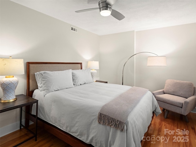 bedroom with ceiling fan, visible vents, and wood finished floors