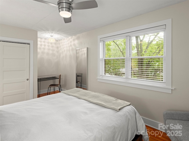 bedroom featuring ceiling fan, baseboards, and wood finished floors